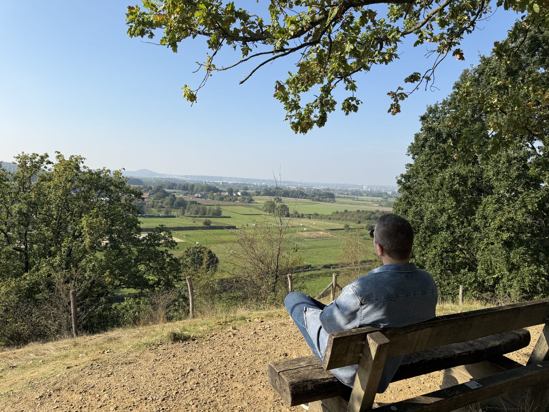 Iemand op een bankje kijkt rustig uit over het landschap